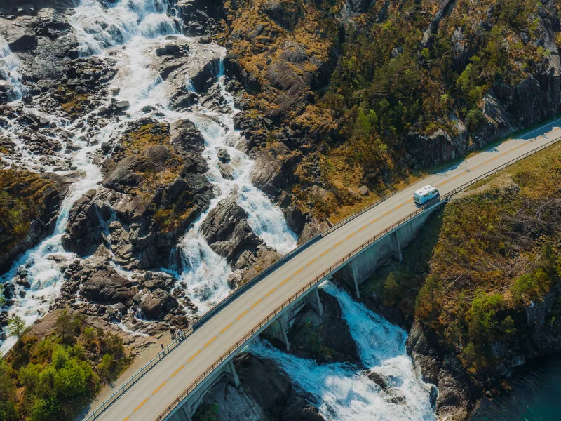Casa rodante cruzando un puente sobre una cascada